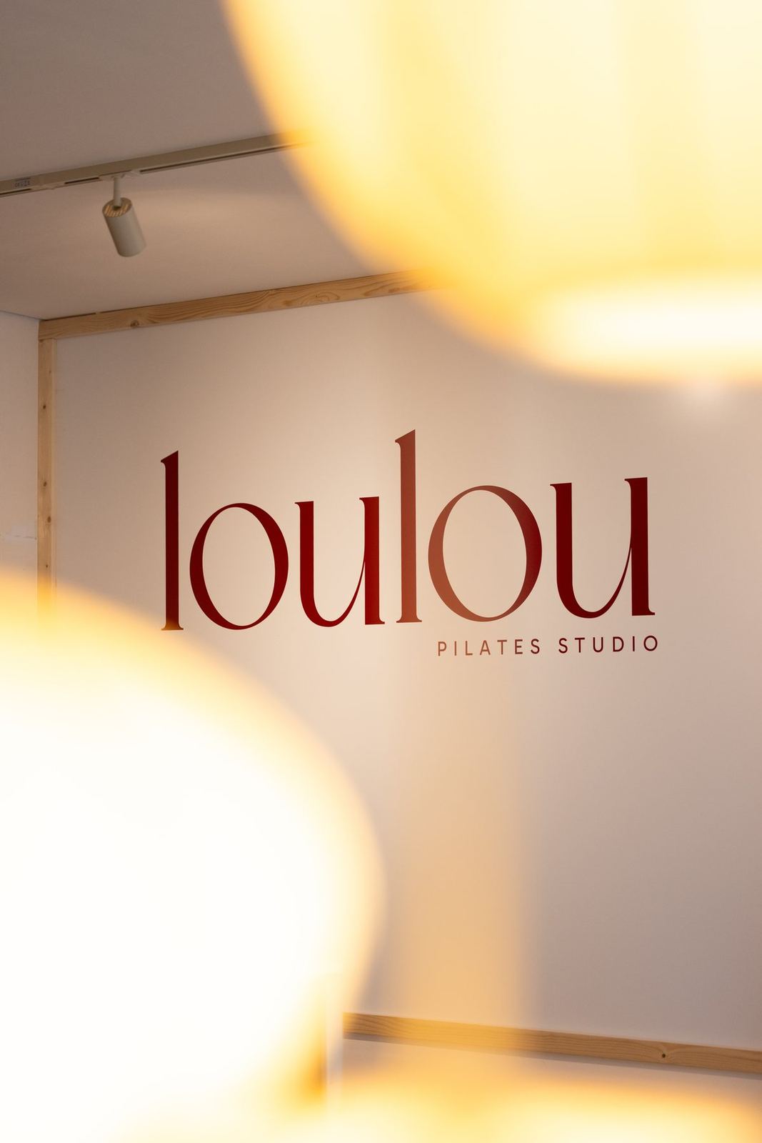 Het loulou-logo op de muur van de studio, door het warme licht van de lampen