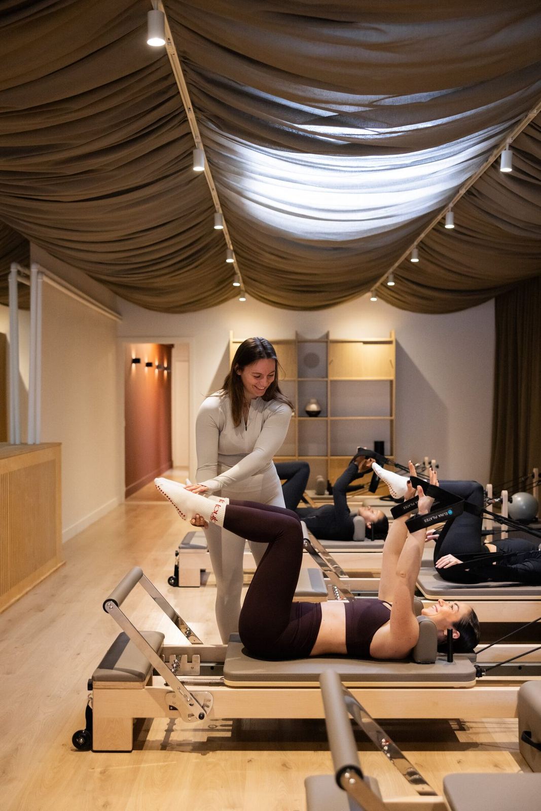 Alessia corrigeert de beenhouding van een deelnemer op de reformer